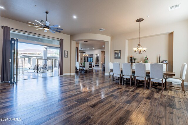 dining room with ceiling fan with notable chandelier and dark wood-type flooring