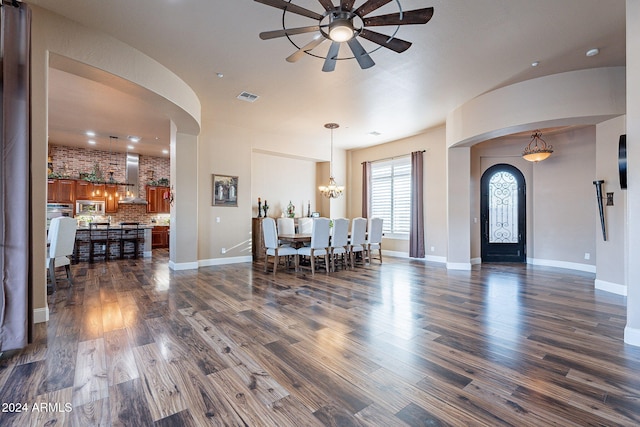 dining area with ceiling fan with notable chandelier and dark hardwood / wood-style floors