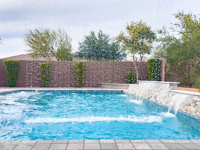 view of swimming pool with pool water feature