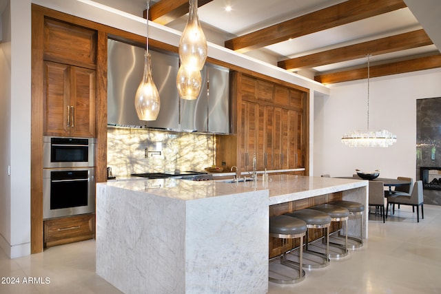 kitchen featuring pendant lighting, a kitchen island with sink, backsplash, stainless steel appliances, and light stone counters