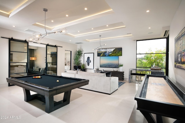 game room with pool table, a tray ceiling, tile floors, and a barn door