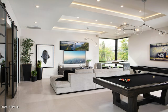 recreation room featuring light tile floors, a barn door, a tray ceiling, and pool table