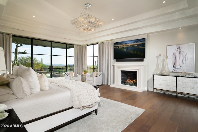 bedroom featuring a tray ceiling, dark hardwood / wood-style floors, and an inviting chandelier