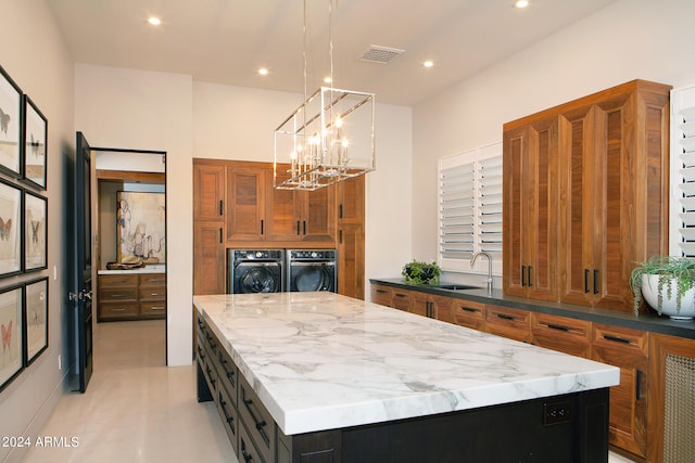 kitchen with washer and dryer, a kitchen island, oven, sink, and hanging light fixtures