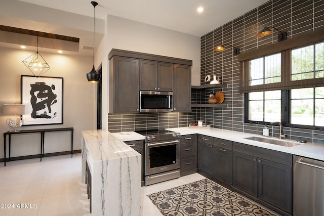 kitchen with dark brown cabinetry, light tile floors, tasteful backsplash, decorative light fixtures, and stainless steel appliances