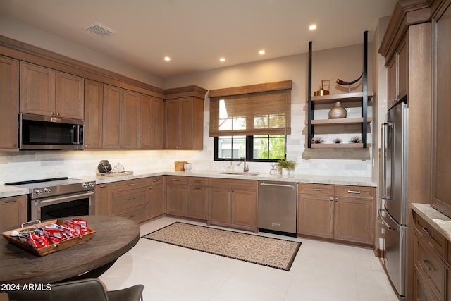 kitchen featuring sink, high end appliances, tasteful backsplash, and light tile floors