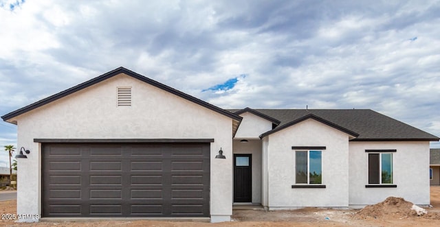 view of front of house with a garage, a shingled roof, and stucco siding