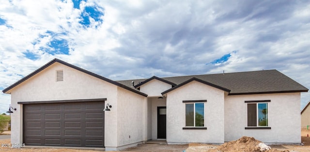 ranch-style house featuring an attached garage, roof with shingles, and stucco siding