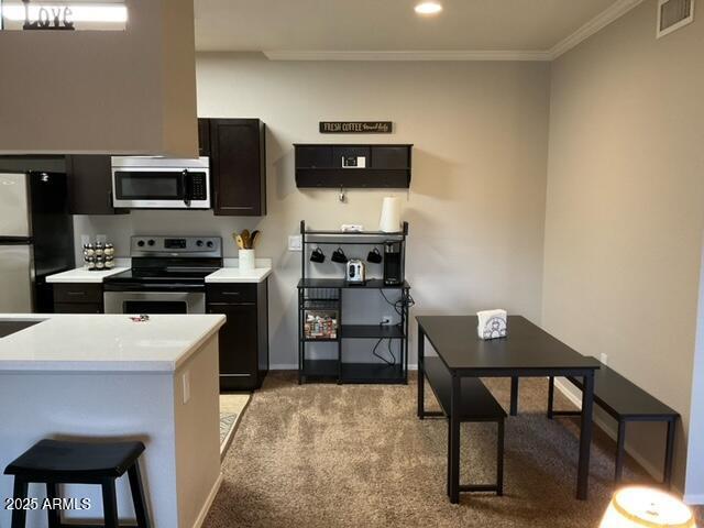 5345 E Van Buren St Unit 370, Phoenix, AZ 85008 - kitchen featuring stainless steel appliances, light countertops, light colored carpet, crown molding, and baseboards
