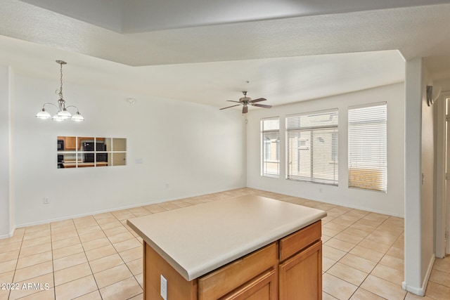 kitchen featuring light tile patterned flooring, ceiling fan with notable chandelier, pendant lighting, and a center island