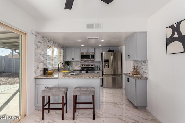 kitchen featuring tasteful backsplash, gray cabinetry, kitchen peninsula, and stainless steel appliances