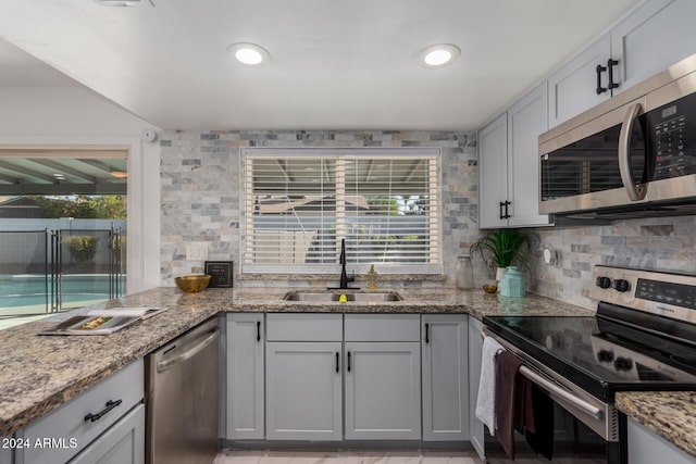 kitchen with light stone countertops, sink, appliances with stainless steel finishes, and tasteful backsplash