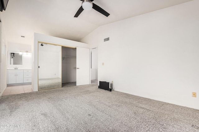 unfurnished bedroom featuring a closet, visible vents, carpet flooring, vaulted ceiling, and a sink