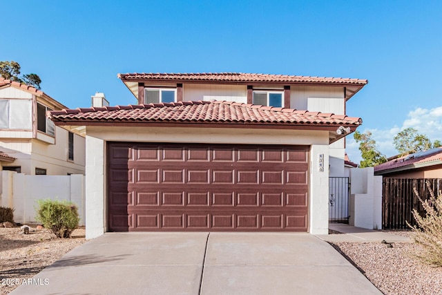 mediterranean / spanish home with a garage, driveway, fence, and a tiled roof