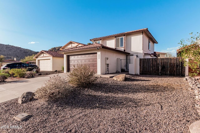 view of front facade featuring an attached garage, a mountain view, fence, concrete driveway, and stucco siding