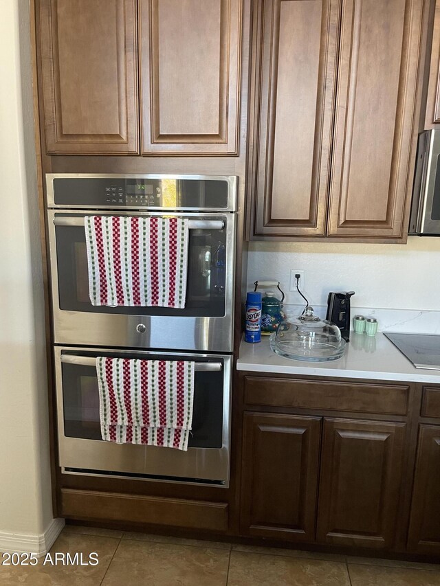 kitchen featuring black electric stovetop, double oven, and light tile patterned floors