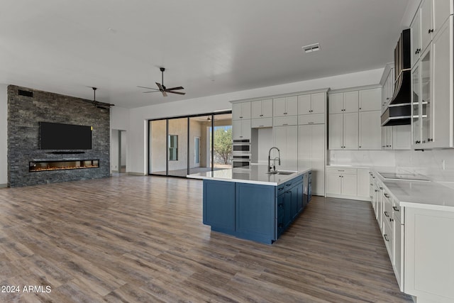 kitchen featuring a fireplace, white cabinets, ceiling fan, sink, and hardwood / wood-style floors