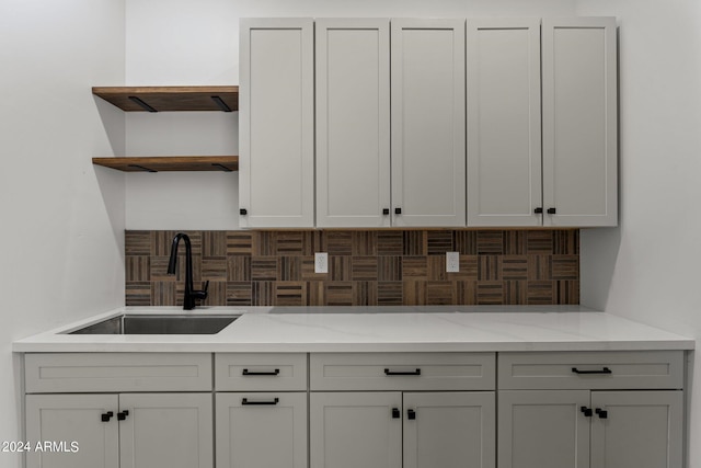 kitchen with light stone countertops, backsplash, and sink