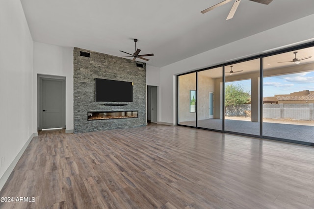 unfurnished living room with ceiling fan, a fireplace, and wood-type flooring