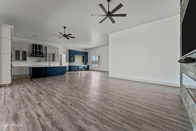 unfurnished living room featuring hardwood / wood-style floors, sink, and ceiling fan