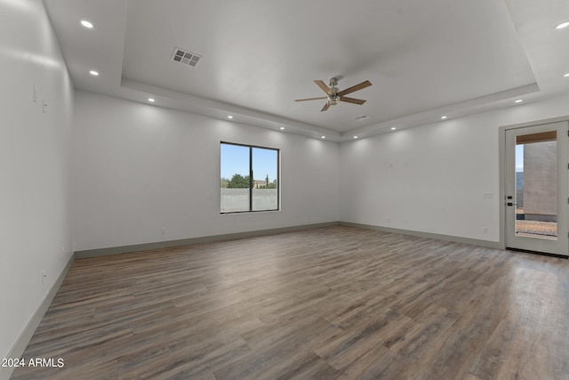 unfurnished room with hardwood / wood-style flooring, ceiling fan, and a raised ceiling