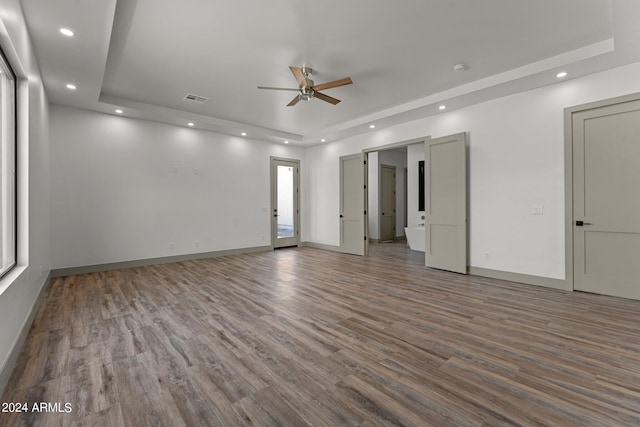 unfurnished room with wood-type flooring, a raised ceiling, and ceiling fan