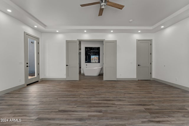 unfurnished living room with ceiling fan, a raised ceiling, and hardwood / wood-style floors