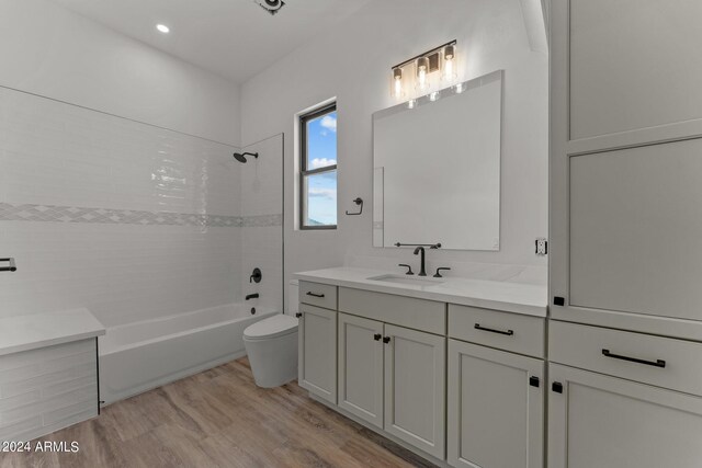 full bathroom with tiled shower / bath combo, hardwood / wood-style flooring, vanity, and toilet