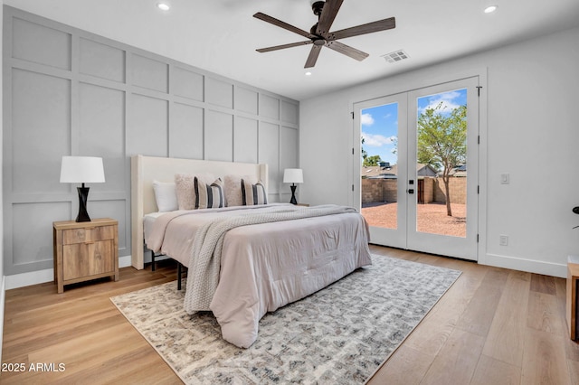 bedroom featuring french doors, a decorative wall, access to outside, recessed lighting, and light wood-style flooring