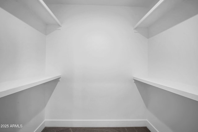 spacious closet featuring dark carpet