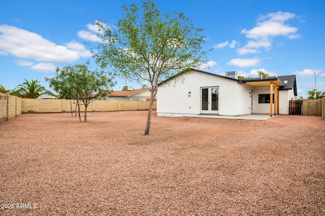 back of house featuring french doors, a fenced backyard, stucco siding, and a patio