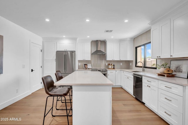 kitchen featuring wall chimney range hood, premium appliances, a sink, a center island, and a kitchen bar