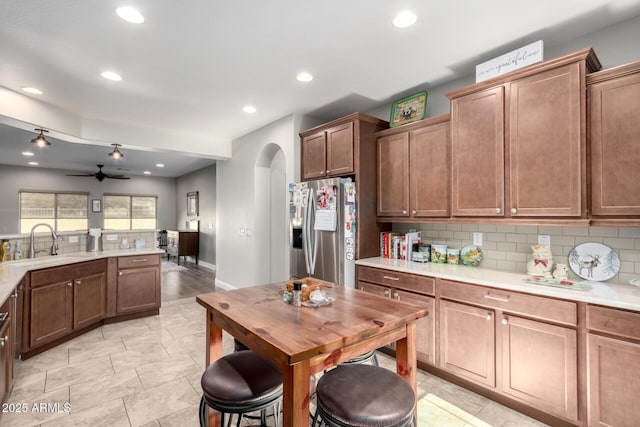 kitchen with sink, backsplash, stainless steel fridge with ice dispenser, and ceiling fan