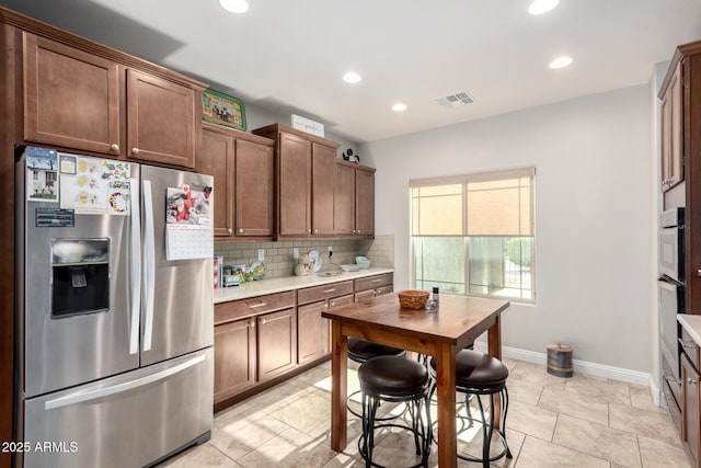 kitchen with stainless steel refrigerator with ice dispenser, backsplash, and light tile patterned floors