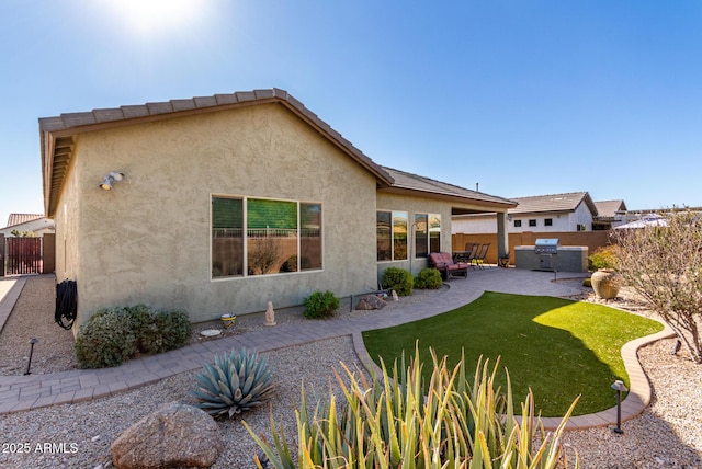 rear view of property with a hot tub, a lawn, and a patio