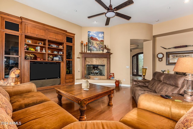 living room featuring baseboards, ceiling fan, a fireplace, wood finished floors, and arched walkways