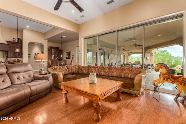 living room with arched walkways, visible vents, a ceiling fan, and wood finished floors