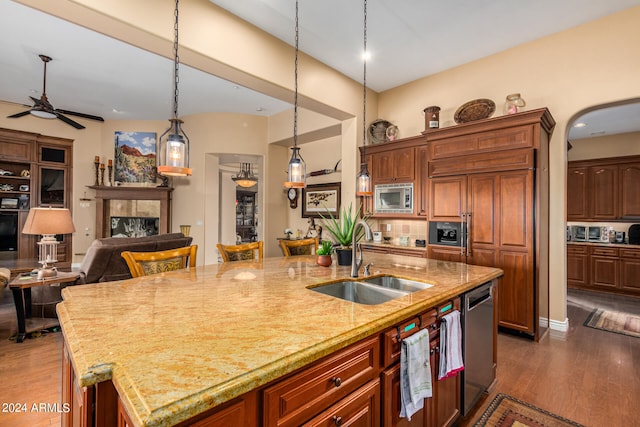 kitchen with appliances with stainless steel finishes, a fireplace, hardwood / wood-style flooring, and a center island with sink