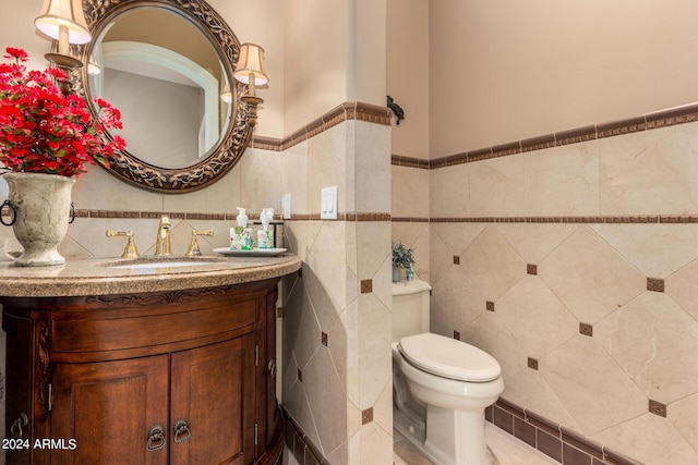 bathroom with tile walls, tile patterned flooring, toilet, and vanity