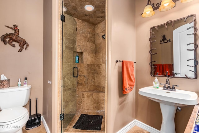 bathroom featuring baseboards, toilet, and a stall shower