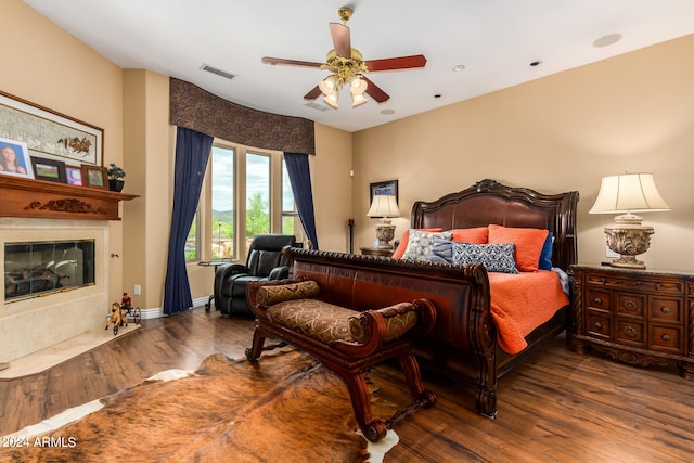 bedroom with dark hardwood / wood-style flooring, a premium fireplace, and ceiling fan