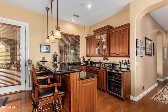 kitchen with kitchen peninsula, decorative light fixtures, a kitchen breakfast bar, hardwood / wood-style flooring, and wine cooler