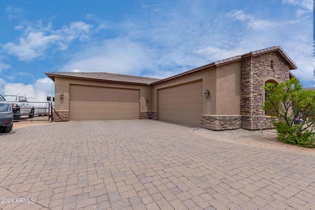 view of front of home featuring stone siding, stucco siding, an attached garage, and decorative driveway