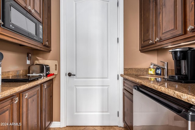 kitchen with a sink, dark stone counters, black microwave, and stainless steel dishwasher