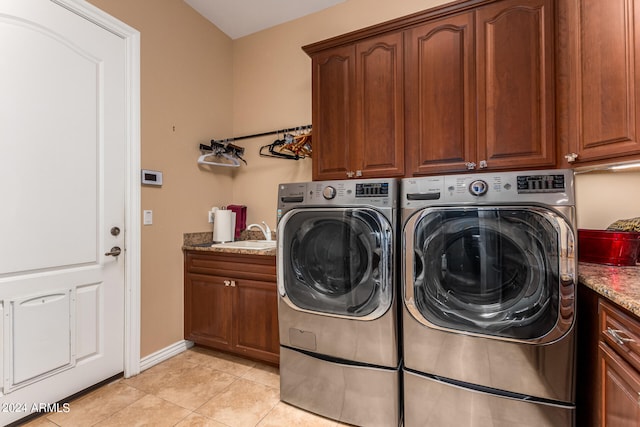 washroom with cabinets, washing machine and clothes dryer, sink, and light tile patterned floors