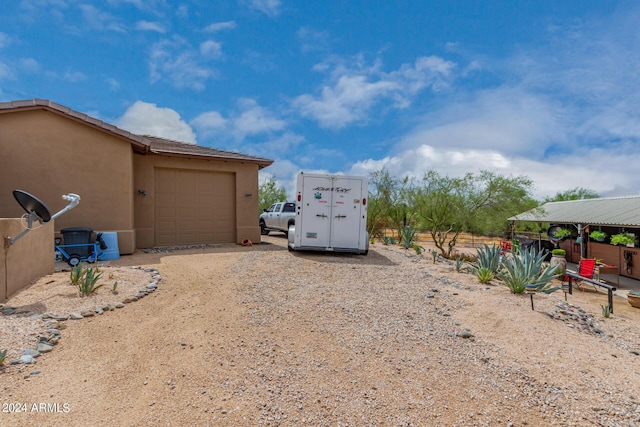 view of yard featuring an attached garage and dirt driveway