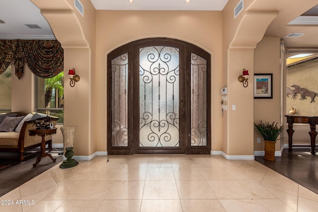 foyer entrance featuring arched walkways, visible vents, and light tile patterned flooring