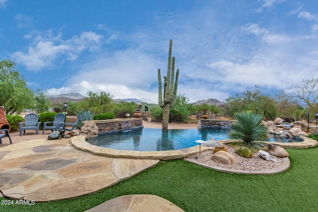 outdoor pool featuring a mountain view, a lawn, and a patio area