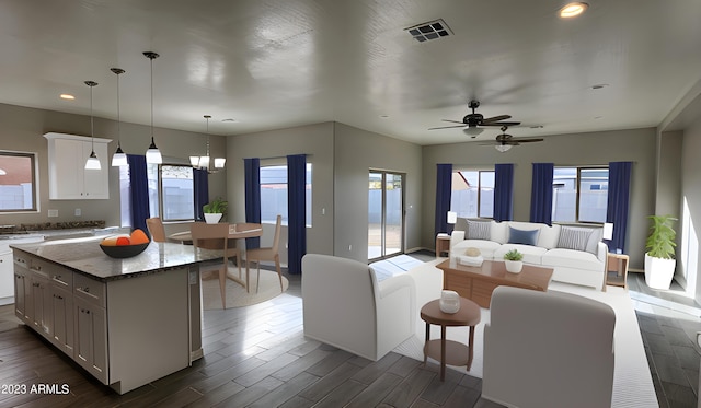 kitchen featuring pendant lighting, dark stone countertops, a kitchen island, and plenty of natural light