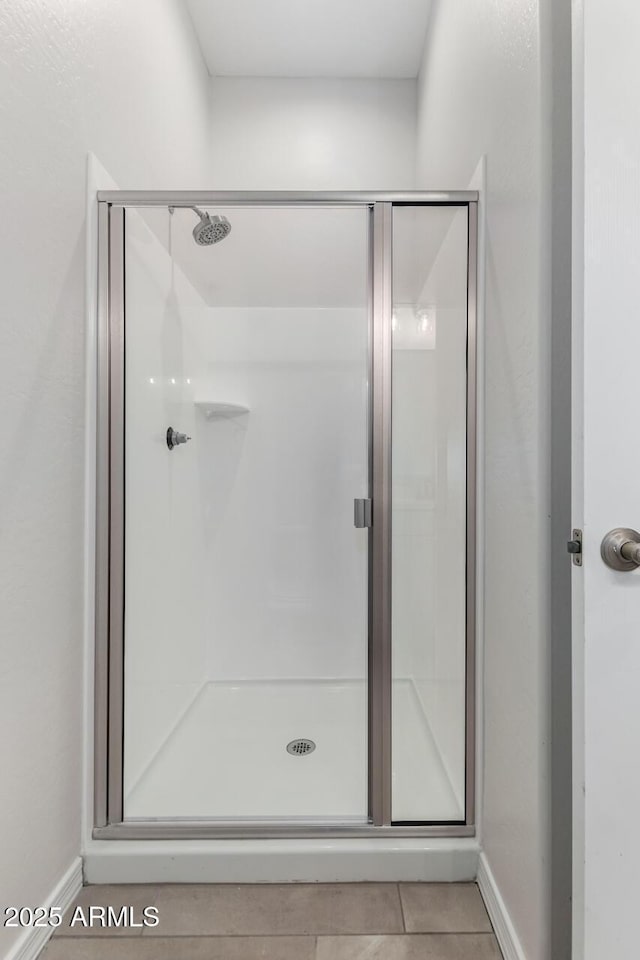 bathroom with a shower with door and tile patterned floors